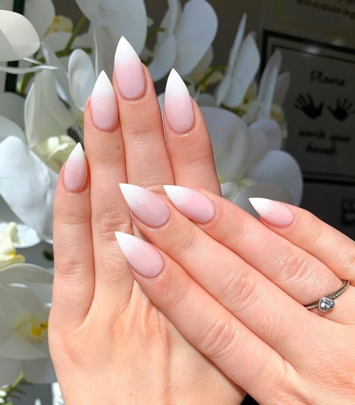 Women's hand with white stiletto gel polish nails – new trend 2025. Nail design. Beauty salon. Spa. Acrylic